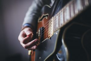 Image showing a close-up of a semi-hollow guitar with a guitarist strumming a chord in guitar lessons