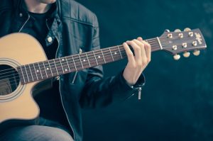 Image showing an acoustic guitarist playing notes from the G Major Scale in guitar lessons