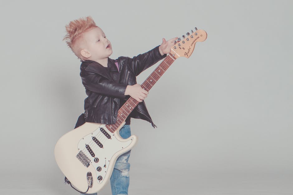 Image showing photograph of young boy holding a Fender Straocaster electric guitar