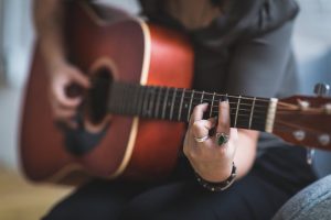 Image showing a female guitarist playing a barre chord on an acoustic guitar in guitar lessons